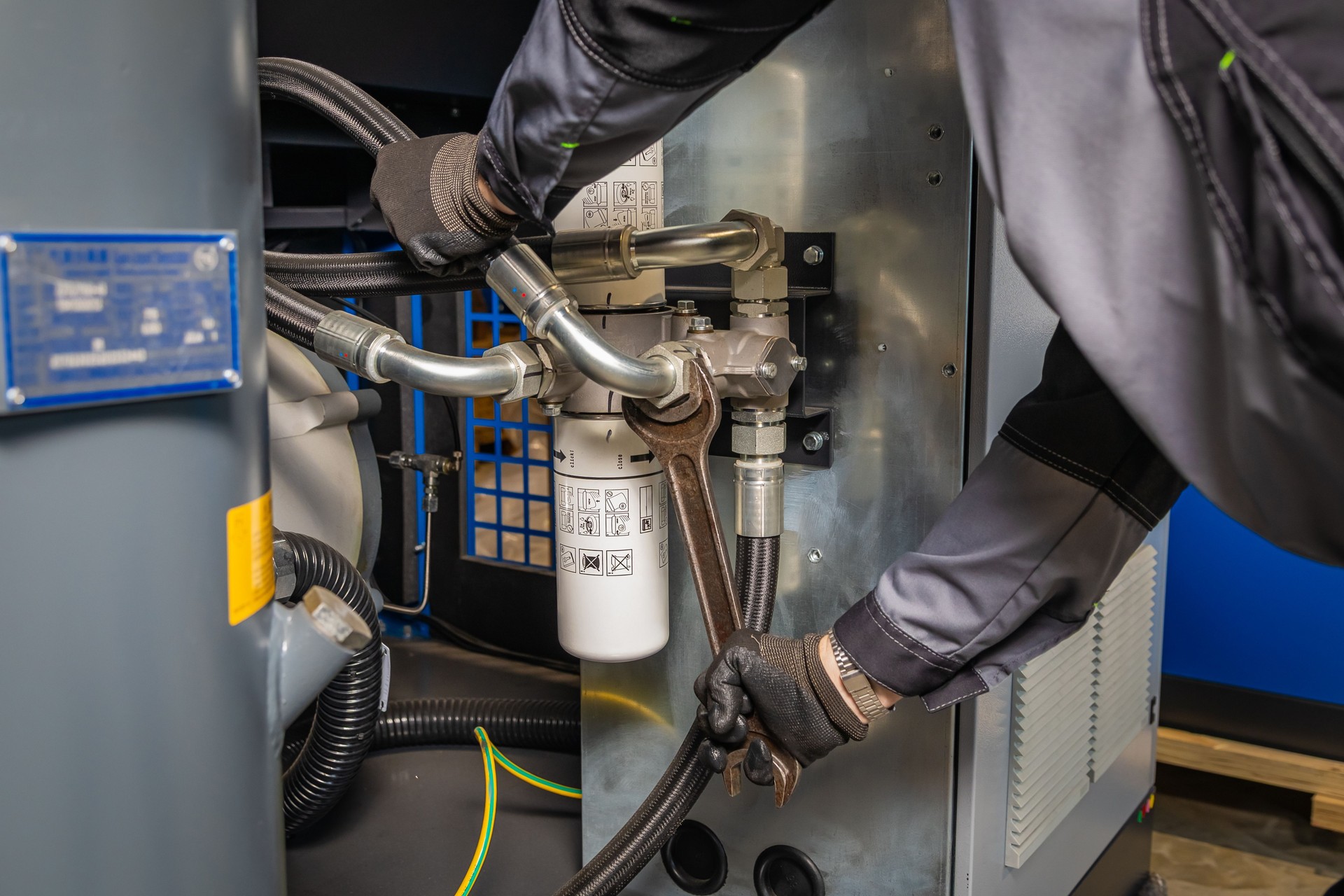 Technician repairing industrial compressor using a wrench