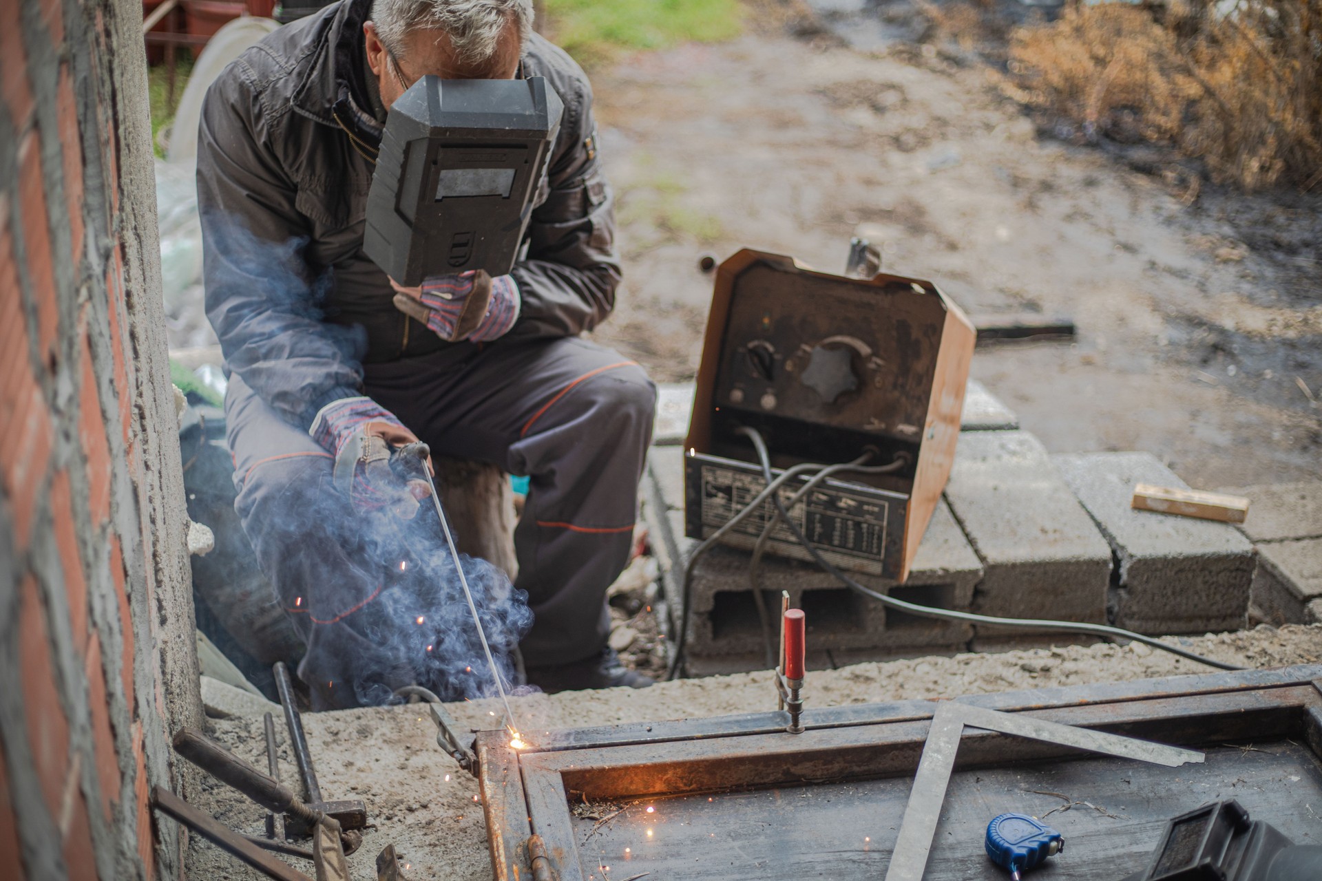 A man joins metal with an electrode, using an electrical device
