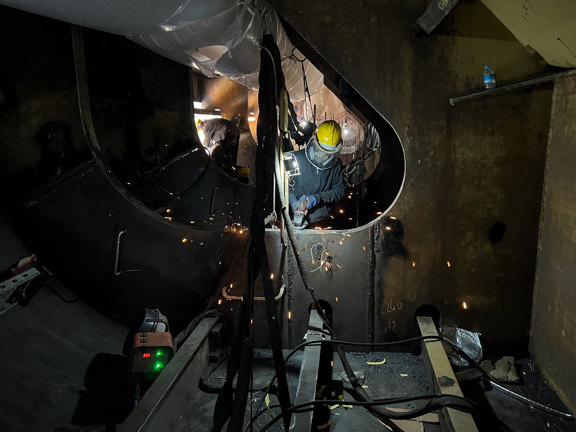 a welder works  inside the ballast tank of a gas tanker ship in a dry dock